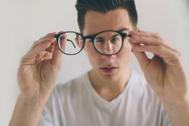 Man holding his eyeglasses Man holding his eyeglasses